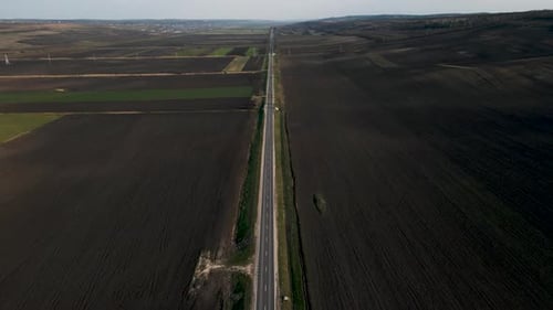 Luftaufnahme einer Straße zwischen landwirtschaftlichen Feldern und grüner Landschaft