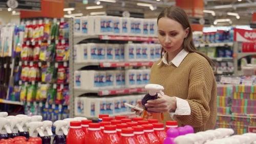 A Young Woman Buying Household Chemicals in a Supermarket