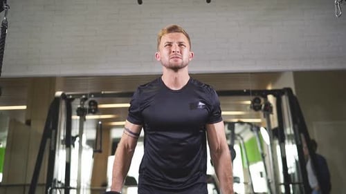 Junger Mann in Sportbekleidung hebt Gewichte, während er im Fitnessstudio trainiert