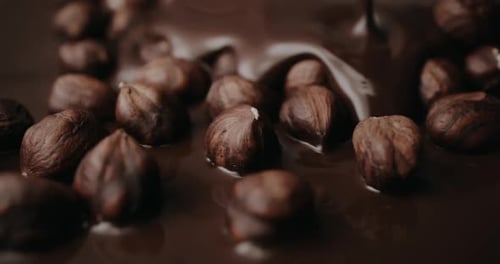 Chocolate Being Poured Over Pile of Hazelnuts