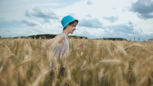 Happy Boy in a Hat Running Across a Golden Wheat Field and Smiling, Boy's Hat Falls
