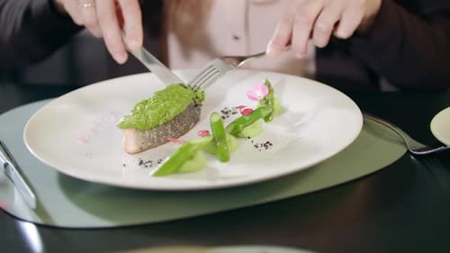 Geschäftsfrau schneidet Fisch mit Messer und Gabel im Restaurant