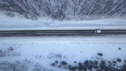 Aerial View on Car Driving Through Winter Forest Road