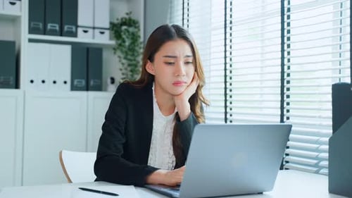 Young Woman Concentrating on Laptop in Modern Office