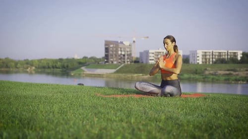 Woman Meditating on Lawn by the Water