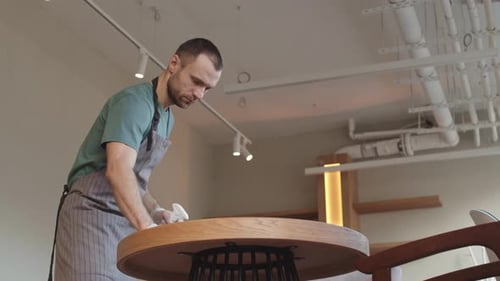 Man Cleaning Table in Cafe