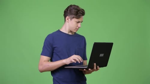 Young Adult Typing on Laptop Against Green Screen