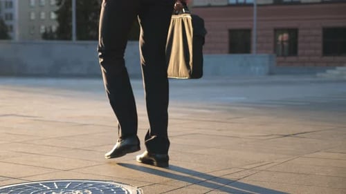 Feet of Young Businessman with a Briefcase Walking in City Street. Business Man Commuting To Work