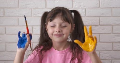 Girl With Painted Hands and Paintbrush Smiling