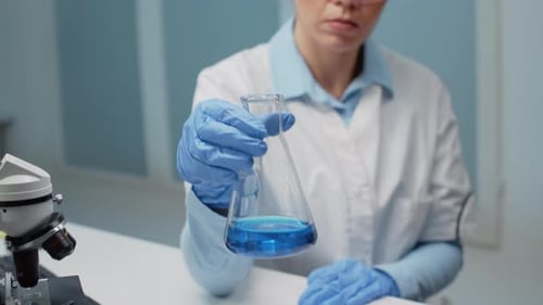 Scientist Examining Blue Liquid in a Flask