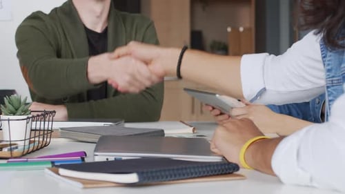 Office Handshake Over Notebooks and Laptop