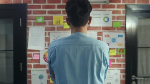Asian creative man standing looking work plan on paper board at office.