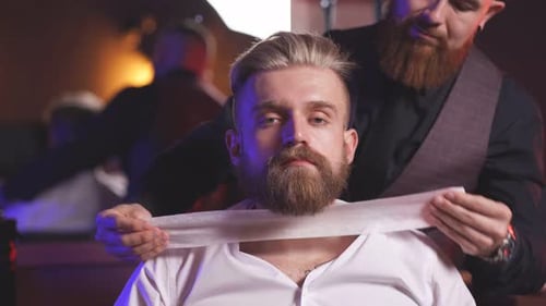 Elegante barbero masculino prepara a un cliente para cortarse la barba