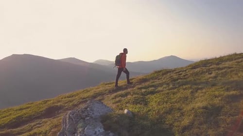 Tourist Hiker with a Backpack in Orange Jacket Walking on Mountain Path in Carpathian Mountains