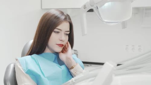 Young Woman Suffering From Toothache Sitting in Dental Chair