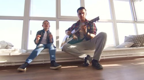 Man and Girl Play Guitar and Sing Together