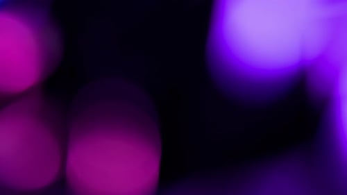 Violet avec particules défocalisées flottantes roses brillantes sur fond noir