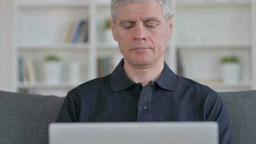 Man Using Laptop While Sitting on Couch
