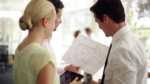 Colleagues Review Blueprint in Modern Office