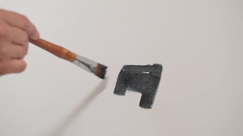 Hand Painting Geometric Shapes with Brush on White Surface