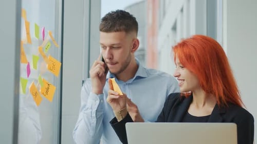 Two Young Adults Brainstorming Together in Modern Office