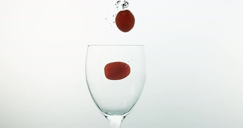 Kirschtomaten, Solanum lycopersicum, Früchte, die vor weißem Hintergrund ins Wasser fallen