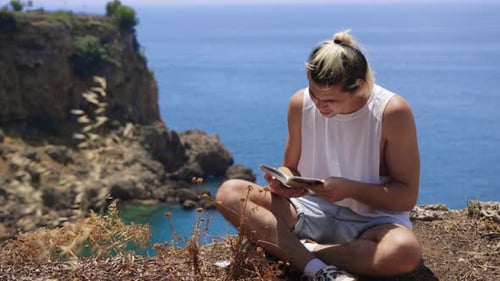 Joven leyendo un libro al borde del acantilado