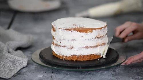 Confectioner Woman is Smearing Cream on Sides of Cake Using Spatula Closeup View