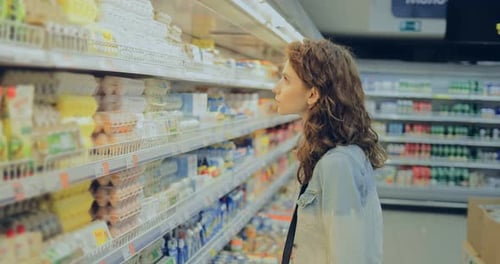 Young Lady Picks Eggs on a Shelf in a Supermarket