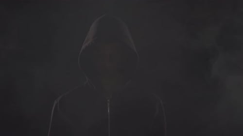 Man in Hoodie Standing in Dark Smoke