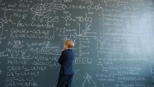 Little Boy Thinking Looking at Formulas Written on Chalkboard Wall in College