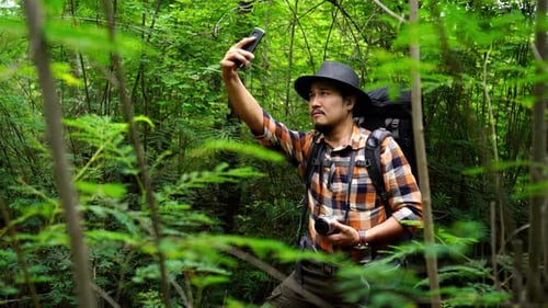 man traveler with backpack using smartphone to taking a selfie in the natural forest