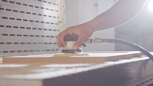 Slow motion of a worker polishing a cabinet door in a furniture factory