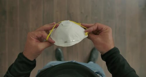 Man Inspecting Protective Face Mask