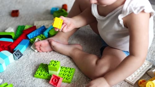 Caucasian Child a Little Girl is Playing in the Constructor at Home