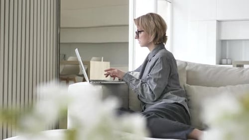 Woman Working on Laptop at Home on Couch