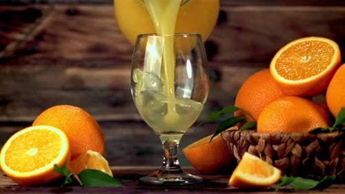 Pouring Fresh Orange Juice into Glass on Wood Table
