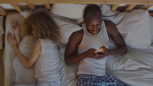 Mujer durmiendo mientras un hombre usa el teléfono