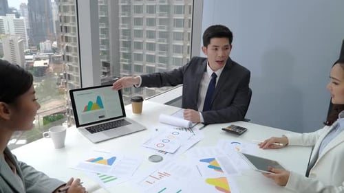 Young Asian businessman presenting sales information to team in the meeting