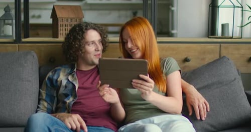 Couple Relaxing on Couch Using Tablet Together