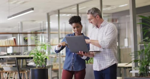 Colleagues Discussing Project on Laptop in Modern Office