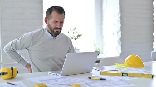 Young Architect with Back Pain Using Laptop in Office