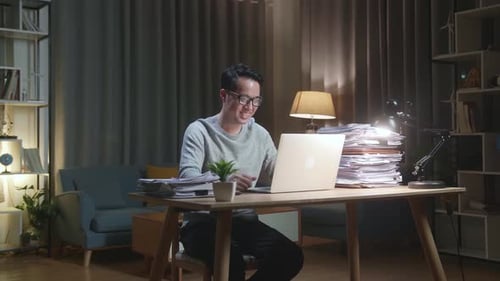 Smiling Man Working on Laptop at Desk