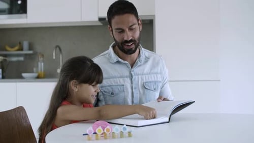Father and Daughter Read a Book Together at Home
