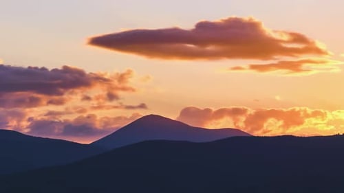 Beautiful Evening Panoramic Landscape with Bright Setting Sun Over Distant Mountain Peaks at Sunset