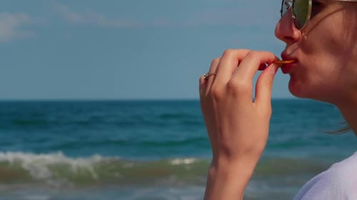Woman eating potato chips at seaside