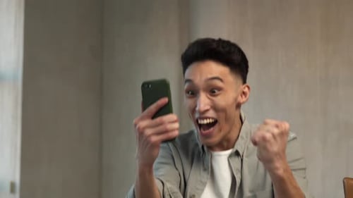 Excited Young Adult Celebrates Receiving Money on Phone