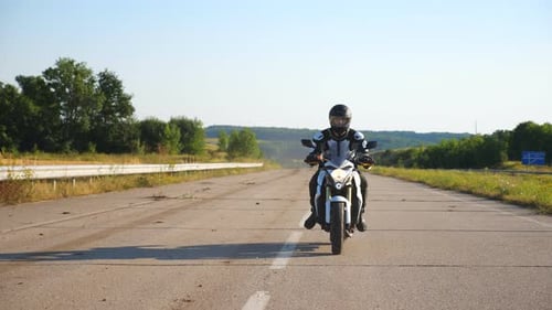 Motorcyclist Rides White Bike on Rural Road