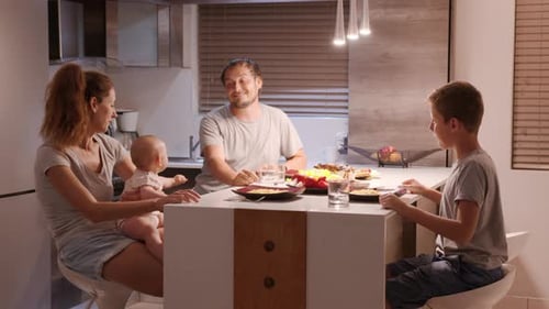 Family Eating Spaghetti in Modern Kitchen