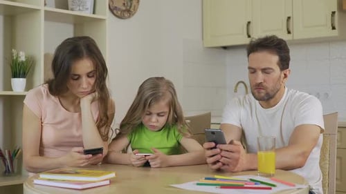 Family Using Smartphones at Kitchen Table